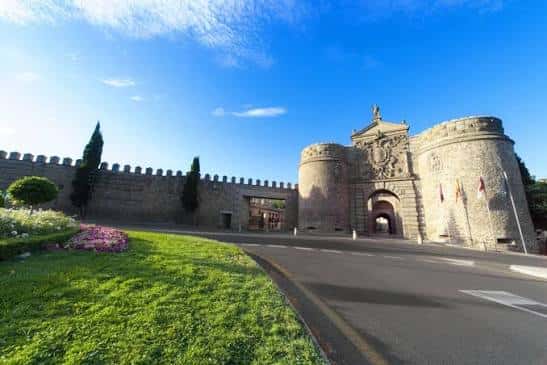 Enfoque amplio de la Puerta de Bisagra con césped y camino de acceso bajo cielo azul