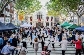Gente bailando en la plaza durante un evento festivo con toldos y decoración