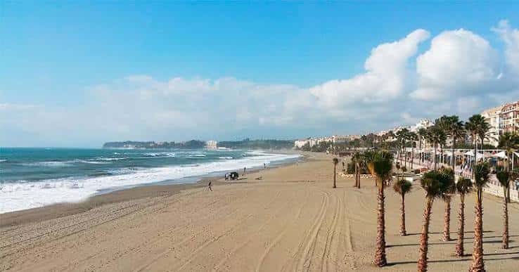 Vista panorámica de la playa con olas y edificios al fondo