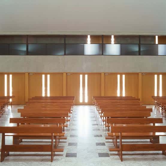 Interior de la iglesia mostrando las naves con bancos de madera y luz natural entrando por las ventanas