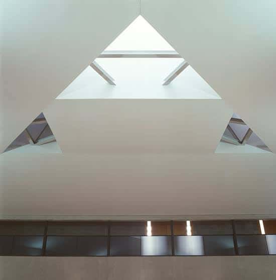 Detalle arquitectónico del interior mostrando el techo con lucernario triangular y estructura geométrica