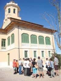 Grupo de visitantes frente a la fachada principal de la Torre Lluvià con su característica torre