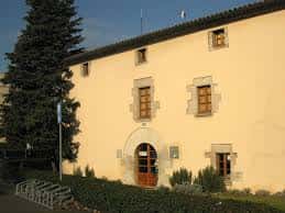 Fachada principal de la Masia de les Tres Torres con puerta de madera y ventanas con marcos de piedra