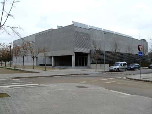 Fachada frontal del Pavelló Municipal de Can Bassa con vehículos aparcados