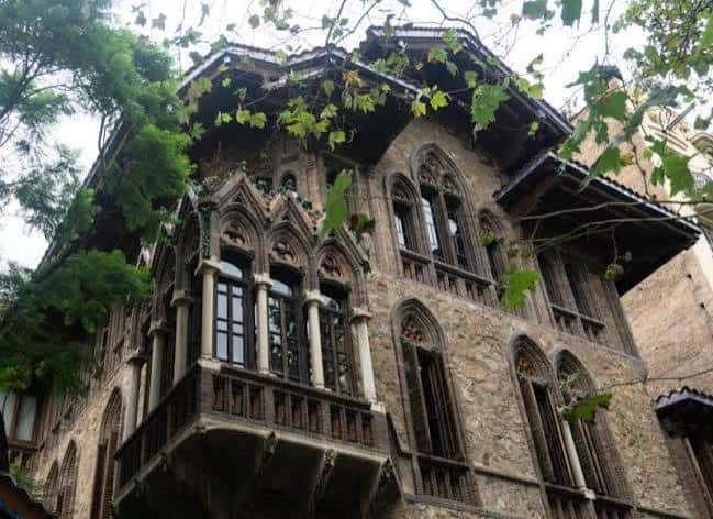 Detalle arquitectónico de la fachada lateral con ventanas góticas y balcones de piedra