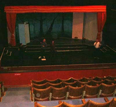 Escenario del teatro con cortinas rojas y butacas frente al escenario