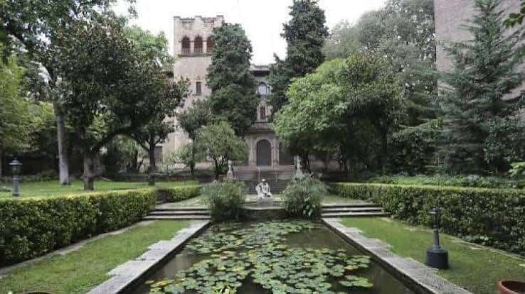Jardín formal con estanque de nenúfares y fachada del palacio