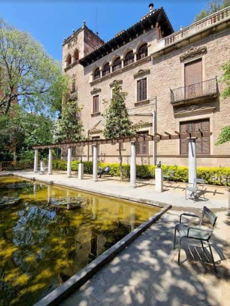 Patio exterior con pérgola y estanque frente al edificio principal