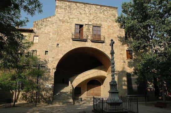 Entrada monumental con arco de piedra y cruz en el patio