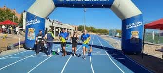 Atletas cruzando la meta en pista azul con arco inflable
