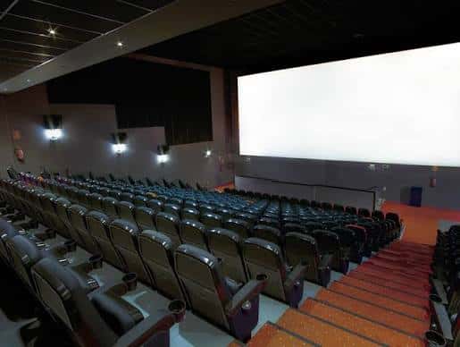 Interior de sala de cine con butacas reclinables y alfombra roja