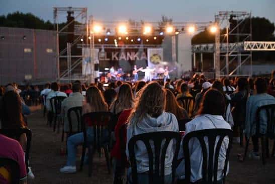Concierto en vivo en el auditorio al aire libre con público sentado y escenario iluminado