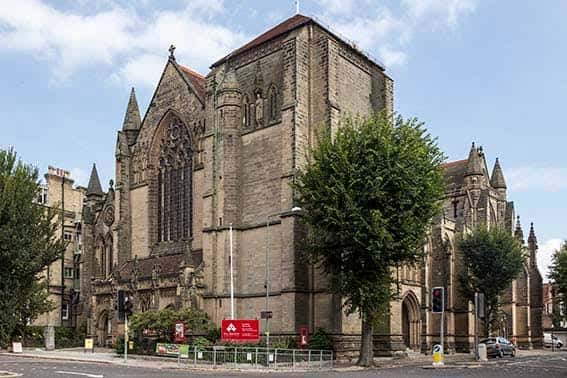 Vista frontal de la iglesia rodeada de árboles y señalización urbana en Brighton