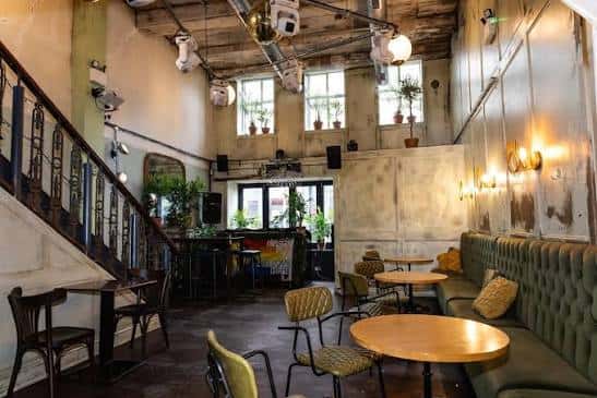 Interior del Oculist con estilo industrial, sofás verdes y ambiente acogedor