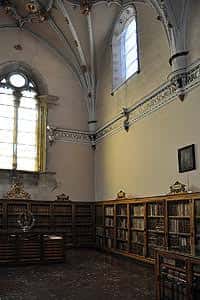 Interior gótico de la biblioteca con bóvedas de piedra y vitrales