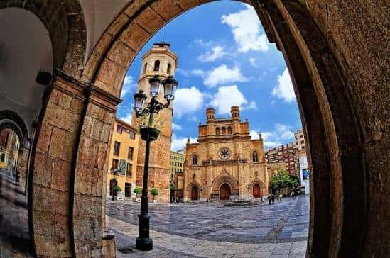 Plaza Mayor vista desde un arco, con la torre y la fachada de la iglesia al fondo