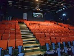 Interior del teatro mostrando las gradas con asientos naranjas y azules
