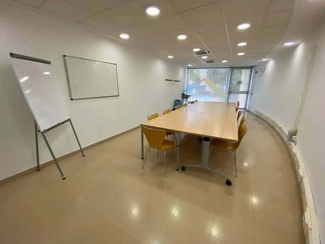 Sala de reuniones equipada con mesa larga y pizarra móvil