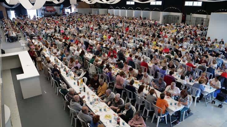 Gran banquete en el centro de congresos con cientos de personas sentadas a mesas largas
