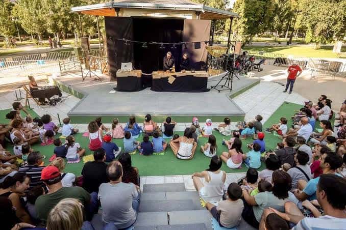 Función de títeres en el teatro del parque con artistas en escena y audiencia familiar