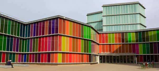Fachada principal del museo con paneles de vidrio multicolor y entrada accesible