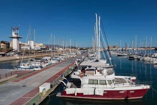 Muelle del puerto con yates amarrados y vista del club al fondo