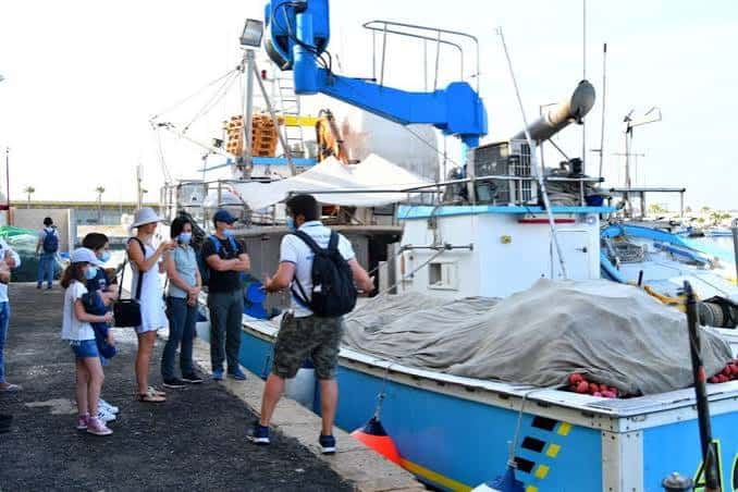 Vista de la lonja del pescado en Torrevieja con turistas observando un barco pesquero
