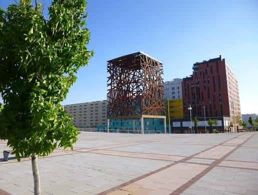 Plaza del Sol con árbol en primer plano y escultura metálica al fondo