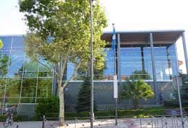 Vista exterior del Centro Cultural Pablo Iglesias con fachada de cristal y banderas