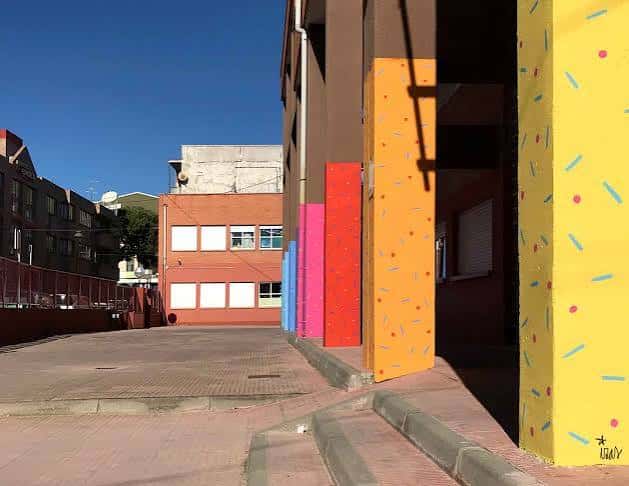 Vista lateral del edificio escolar con columnas pintadas de colores vivos