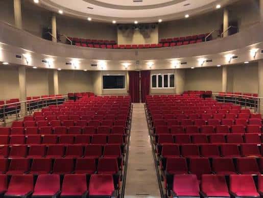Interior del auditorio con butacas rojas y escenario vacío