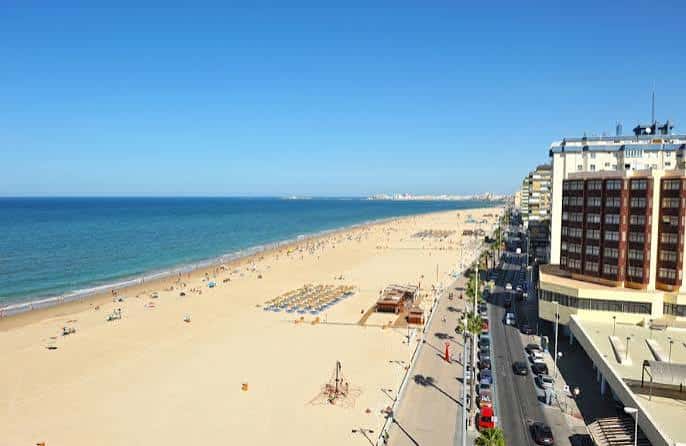 Vista panorámica de la Playa de la Victoria con edificios costeros y mar azul