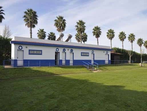 Edificio de vestuarios con palmeras al fondo en el complejo deportivo