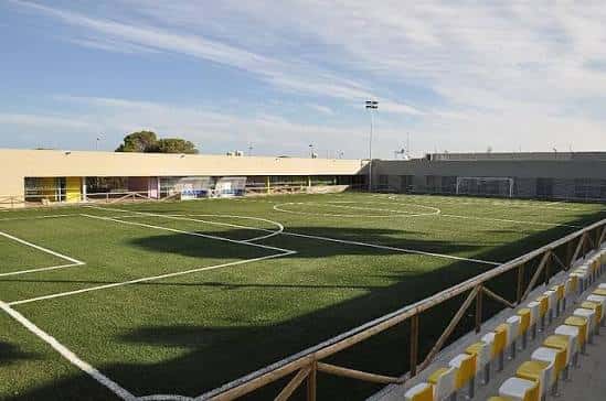 Vista panorámica del campo de fútbol con gradas y césped artificial