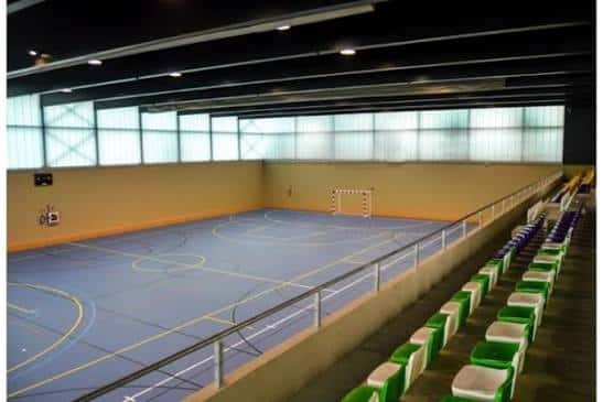 Interior del pabellón deportivo con cancha de baloncesto y gradas