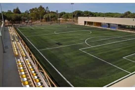 Campo de fútbol exterior con césped artificial y gradas laterales