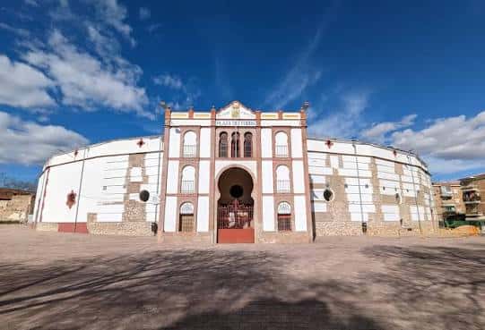 Vista frontal de la Plaza de Toros de Ciudad Real con fachada blanca y detalles arquitectónicos bajo cielo azul