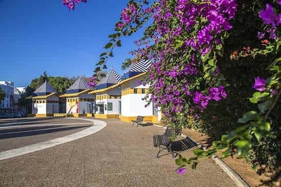 Vista del parque con kioscos de estilo tradicional y flores de buganvilla