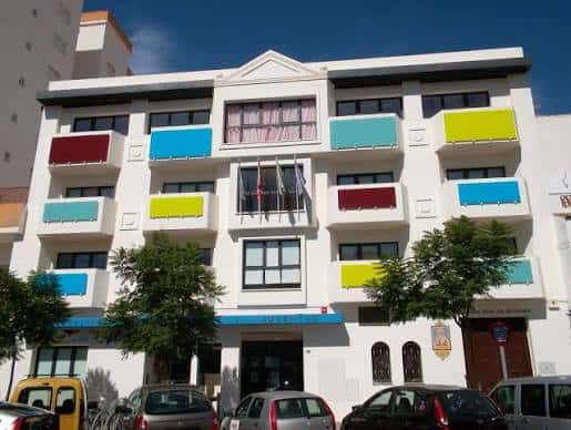 Vista completa del Edificio Colores con árboles y vehículos en primer plano