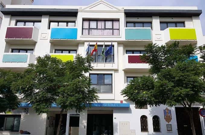 Entrada principal del Edificio Colores con árboles y banderas