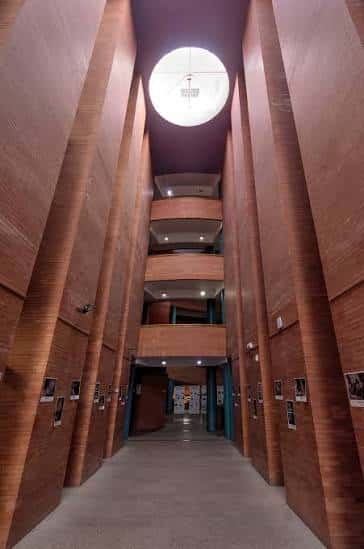 Pasillo central del edificio con paredes de madera, balcones superiores y claraboya circular en el techo