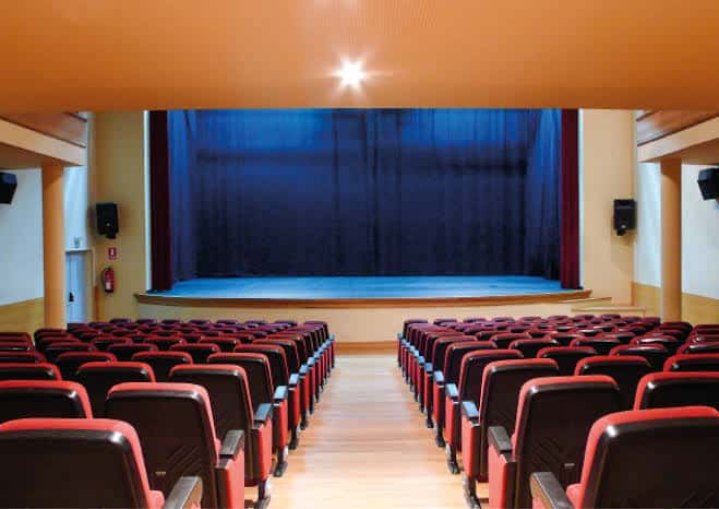 Interior del teatro con escenario cubierto por cortina azul