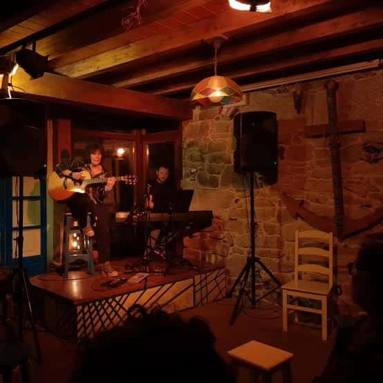 Concierto en vivo en el interior de A Arca da Noe con músicos tocando en un escenario acogedor