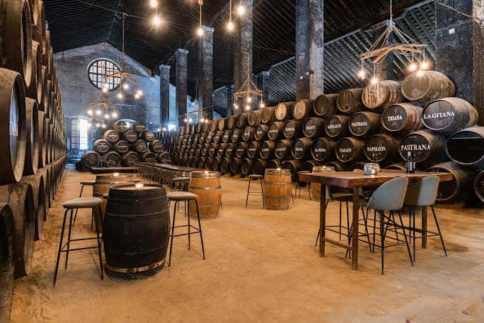 Sala de barricas de Bodegas Hidalgo La Gitana preparada para eventos con mesas y sillas