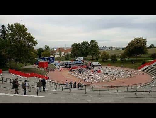 Evento en el anfiteatro con escenario montado y público sentado en sillas blancas