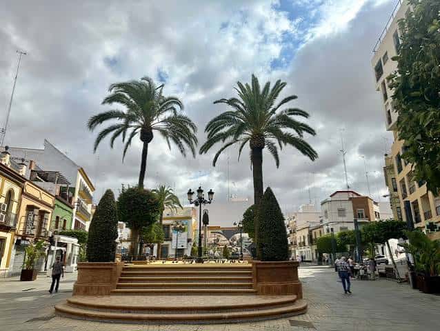 Plaza de la Plazuela con palmeras y escalinata central bajo cielo nublado