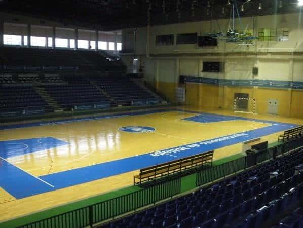 Pista interior de baloncesto con gradas y suelo de madera pulida