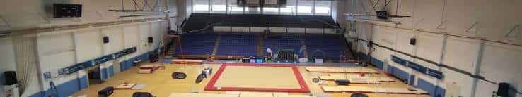 Vista panorámica del interior del polideportivo con zona de gimnasia y gradas azules