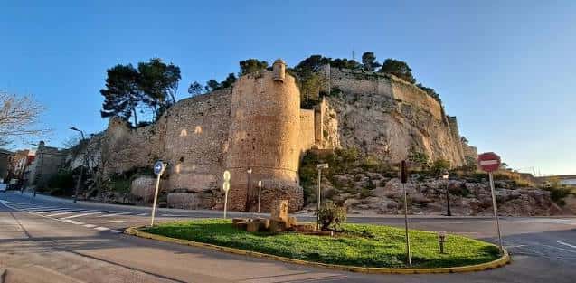 Fachada exterior del castillo al atardecer con torres y muros de piedra