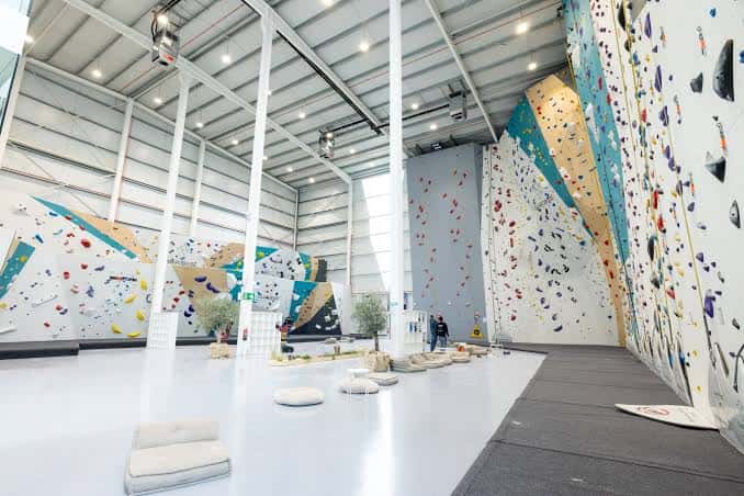 Interior amplio del polideportivo con múltiples paredes de escalada y zona de descanso